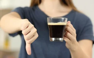 Moça segurando café com dedo polegar virado pra baixo